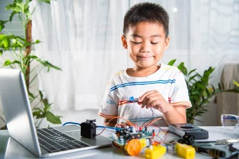 Asian kid boy assembling board into Arduino robot car homework Stock Photos