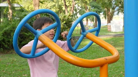 Asian kid boy exercise with wheel equipment at outdoor fitness in public park Stock Footage 62653503