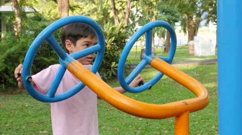 Asian kid boy exercise with wheel equipment at outdoor fitness in public park Stock Footage 62653603