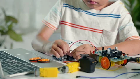 Asian kid boy plugging energy and signal cable to sensor chip with Arduino robot Stock Footage 224409081