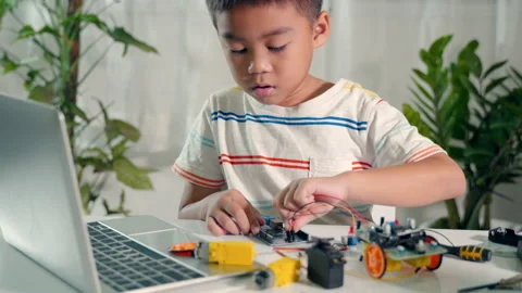 Asian kid boy plugging energy and signal cable to sensor chip with Arduino robot Stock Footage 230588522