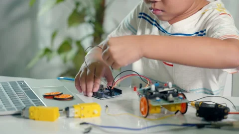 Asian kid boy plugging energy and signal cable to sensor chip with Arduino robot Stock Footage 235903758