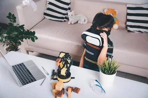 Asian kid boy using VR glasses on robotic arm in workshop Stock Photos