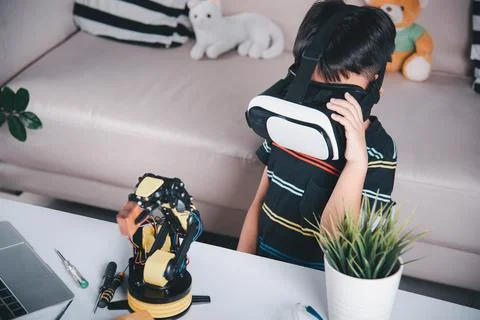 Asian kid boy using VR glasses on robotic arm in workshop 写真素材