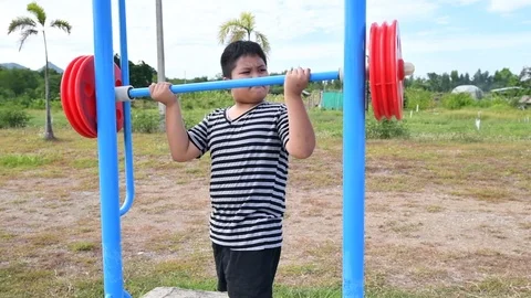 Asian kid exercise with Weight-lifting at outdoor fitness in public park Stock Footage 113339269