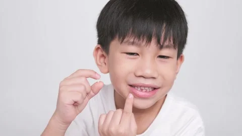 Asian kid holding the first fallen baby milk teeth. Stock Footage 204724217
