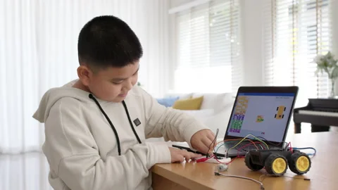 Asian kid make scratch robot car programming at home STEM study online Video stock 158444367