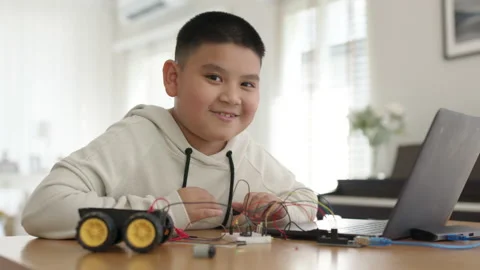Asian kid make scratch robot car programming at home STEM study online Stock Footage 158444387