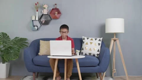 Asian kid sitting on couch using laptop notebook Stock Footage 155748882