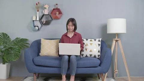Asian kid sitting on couch using laptop notebook Stock Footage 157111922