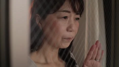 Asian lady looking outside through the window. Tired face. Stock Footage 221084120