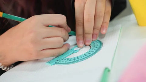 Asian learner precisely checks angles with protractor at desk. Student from Asia Video stock 329889353