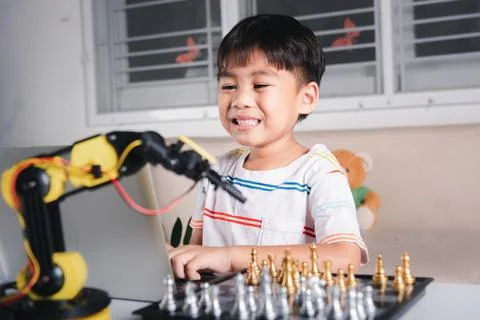Asian little boy programming code to robot machine arm on laptop for play che Stock Photos