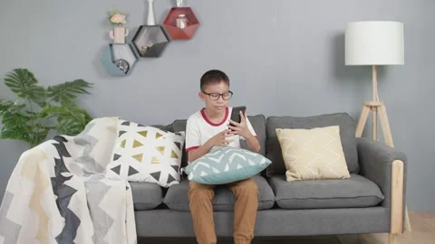 Asian little boy using smartphone while sitting on sofa Stock-Footage 156240037