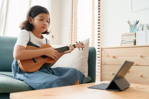 Asian little girl is practicing ukulele playing and learn with a teacher Stock Photos