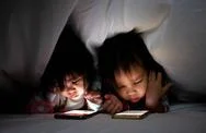Asian Little Girl With Sister Look Cartoon On A Smartphone Under Blanket On Bed Stock Photos