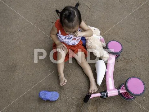 Asian little girl sitting on the ground after falling and getting hurt at knee. Stock Photos
