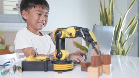 Asian little kid boy using laptop computer check on robotic arm machine in Stock Footage 230419061