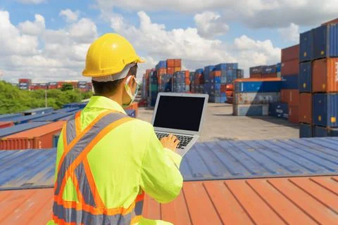 Asian logistic worker engineer man using a laptop computer, working in cargo  Stockfoto's