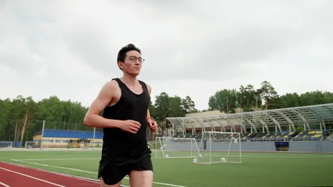 Asian-looking man running on the background of a football field. Stock Footage 255665147