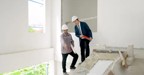 Asian male contractor and engineer walk across unfinished building floor, Stock Footage 336534952