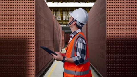 Asian Male Engineer Looking At The Tablet In His Hand With Brick In Stacks Stock Footage 303759995