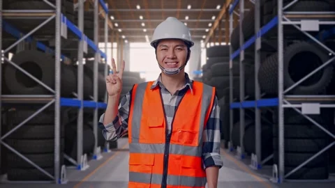 Asian Male Engineer Smiling And Showing Peace Gesture at Tire Warehouse Stock Footage 341786441