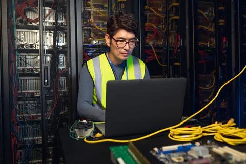 Asian male engineer using a laptop in computer server room Stock Photos