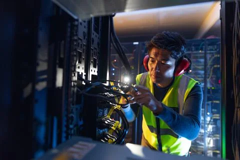 Asian male engineer using smartphone flash while inspecting the server in Stock Photos