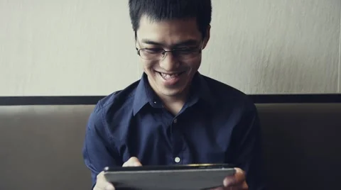 Asian male enjoy using tablet to play game Stock Footage 63397905