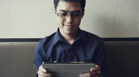 Asian male enjoy using tablet to play game Stock Footage 63397916