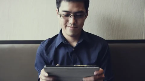 Asian male enjoy using tablet to play game Stock Footage 63398319