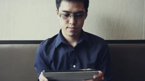 Asian male enjoy using tablet to play game Stock Footage 63398369