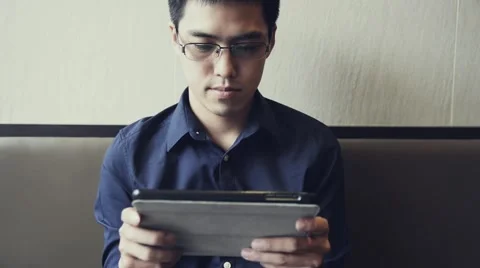 Asian male enjoy using tablet to play game Stock Footage 63399306
