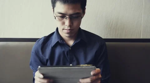 Asian male enjoy using tablet to play game Stock Footage 63399512