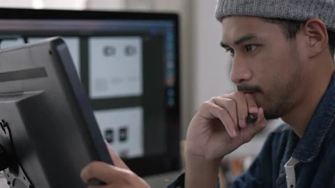 Asian male graphic designer working on computer drawing sketches logo design. Stock Footage 229485953