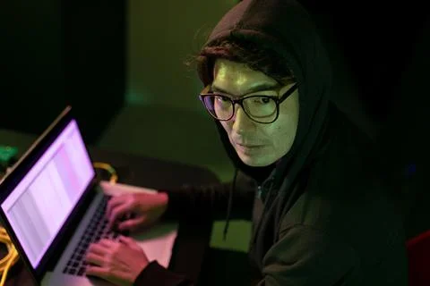 Asian male hacker using a laptop in computer server room 写真素材