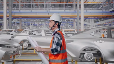 Asian Male Looking At Blueprint While Walking In Car Factory Stock Footage 331580962