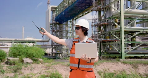 Asian male refinery engineer points walkietalkie across pipeline network while Stock Footage 339651592