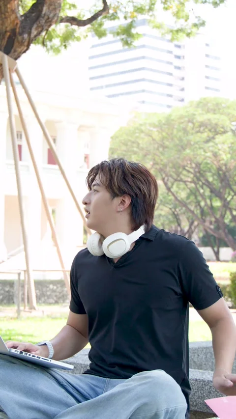 Asian Male Student Using Laptop Outdoors on University Campus Grounds Stock Footage 336352146