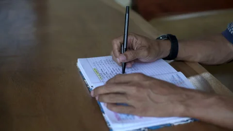 Asian male take a break before continue writing a book while play turning a pen Stock Footage 336034714