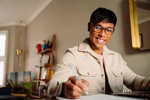 Asian male taking notes while working from home Stock Photos