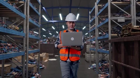 Asian Male Use Computer While Walking at Recycling Warehouse Stock Footage 318076794