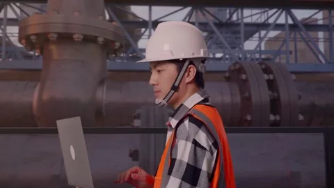 Asian Male Use Computer While Walking with Industrial Pipeline Stock Footage 318079485