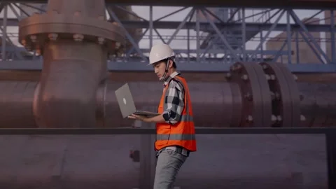 Asian Male Use Computer While Walking with Industrial Pipeline Stock Footage 318080043