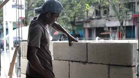 Asian male worker constructing a wall with light brick materials Stock Footage 245337334