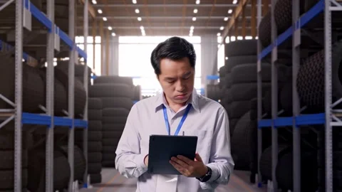 Asian Male Worker Use Tablet And Headache at Tire Warehouse Stock Footage 341786136