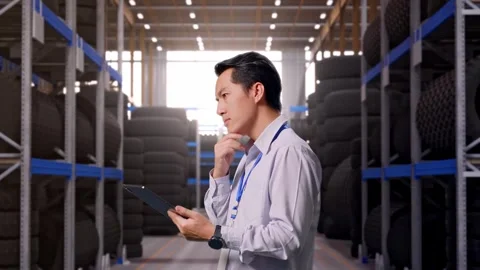 Asian Male Worker Use A Tablet at Tire Warehouse Stock Footage 341786148