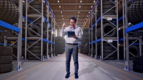 Asian Male Worker Use Tablet And Celebrating at Tire Warehouse Stock Footage 341786228