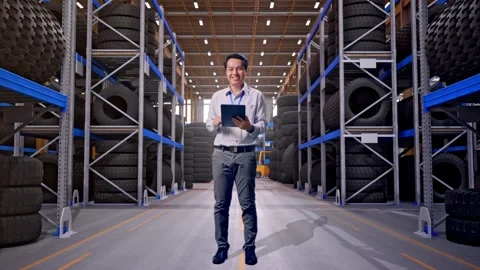 Asian Male Worker Use Tablet And Smile at Tire Warehouse Stock Footage 341786229
